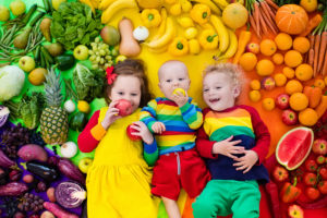 Boy girl and baby with variety of fruit and vegetable. Colorful rainbow of raw fruits and vegetables. Child eating healthy snack. Vegetarian nutrition for kids. Vitamins for children. View from above