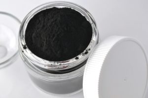 Powdered activated charcoal for facial mask in jar with copy space